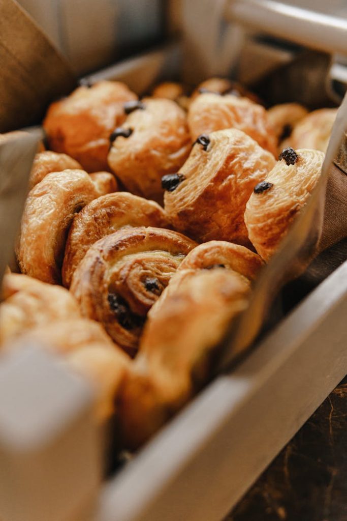 A close-up of freshly baked raisin danish pastries in a bakery setting.